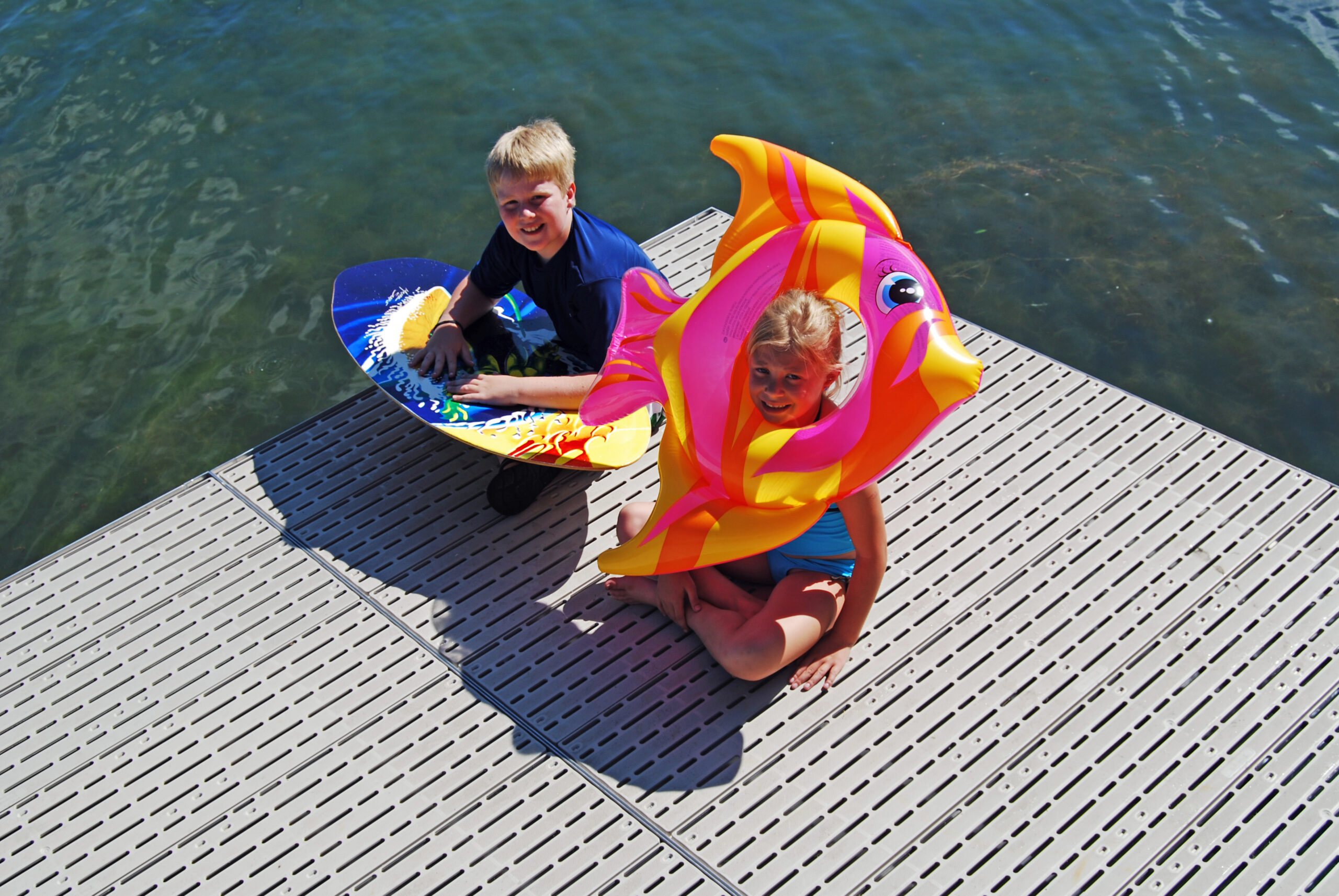 Two kids with floaties sitting on a dock with Titan classic.