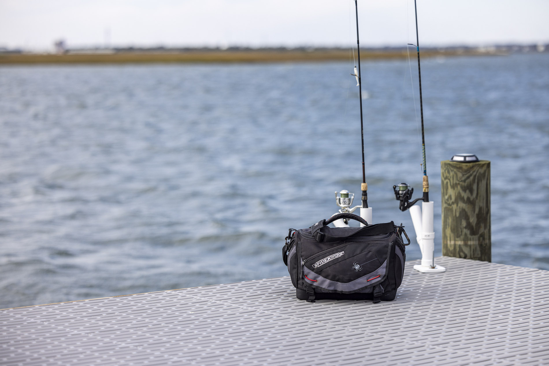 A tackle box and two fishing rods on a platform of titan classic over the blue water.