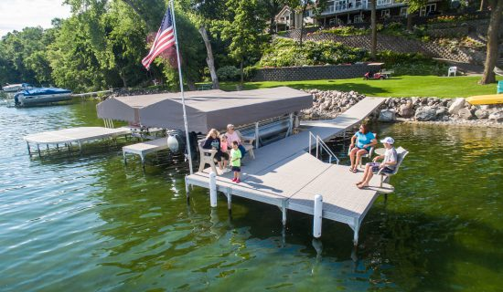 An image of a family sitting at the end of a dock over the water.