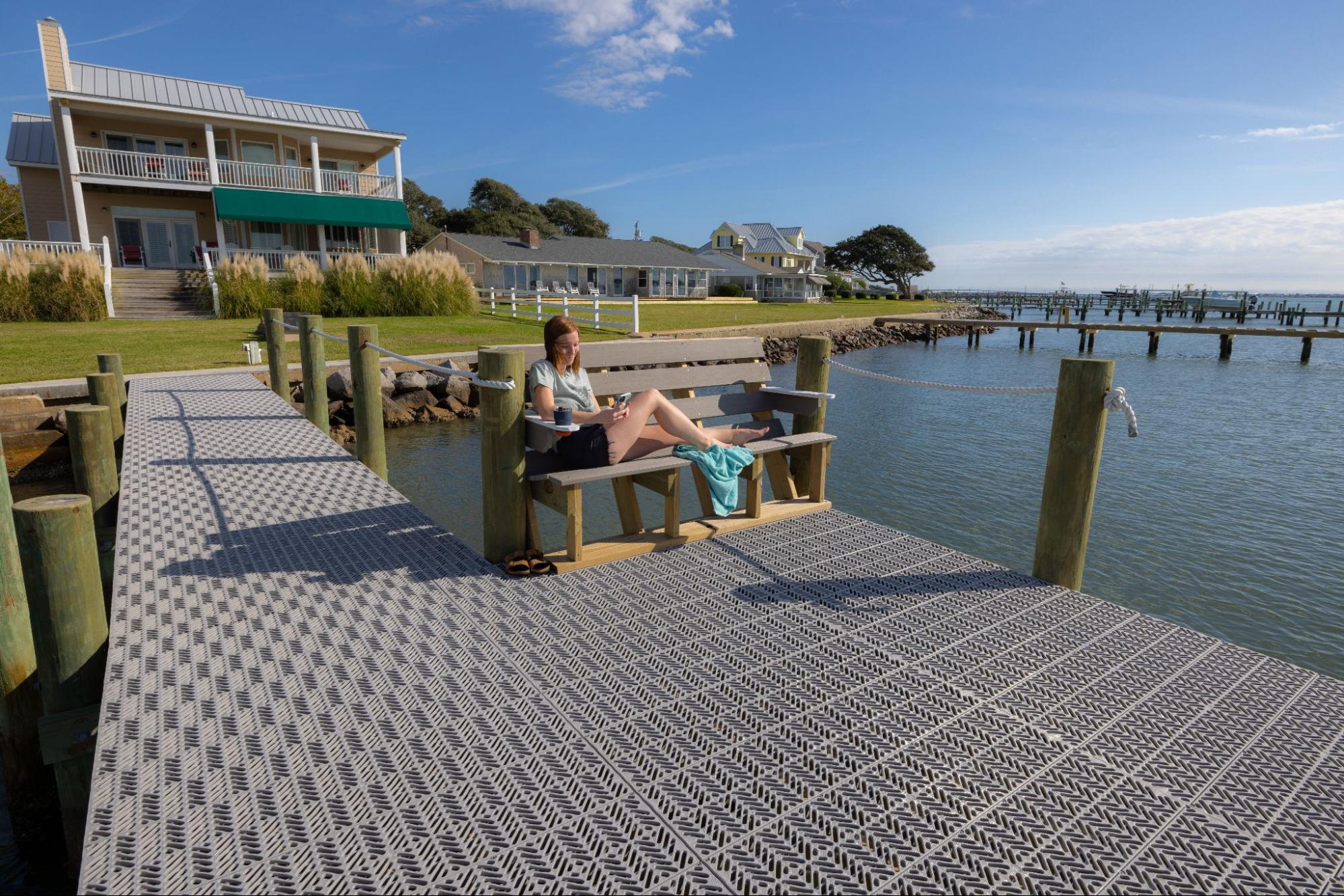 The view of a person sitting on a bench on a deck. The deck is in front of a waterfront home.