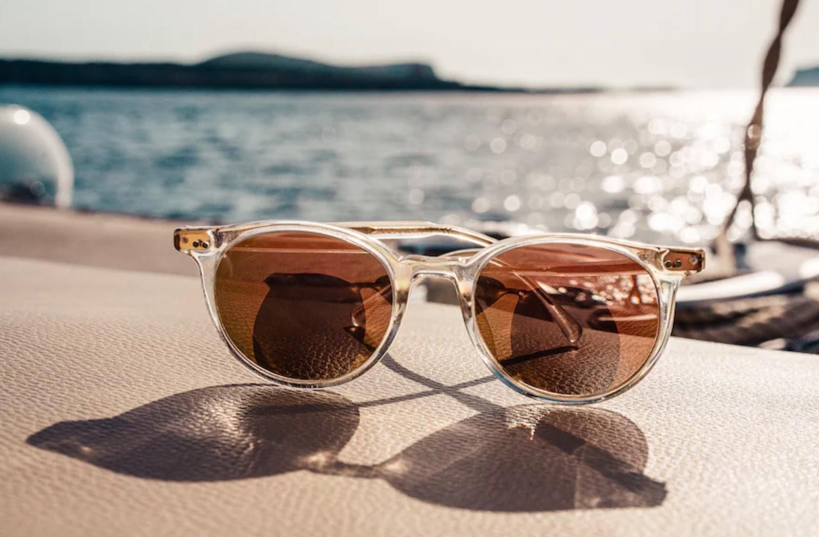 A pair of sunglasses is sitting on the ledge of a boat and casting a shadow. 