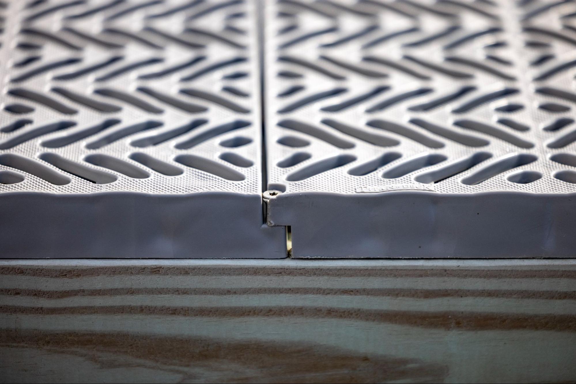 The photo is an extreme close-up shot of a gray deck mounted on a wooden base. The gray docking consists of a zig-zag pattern.