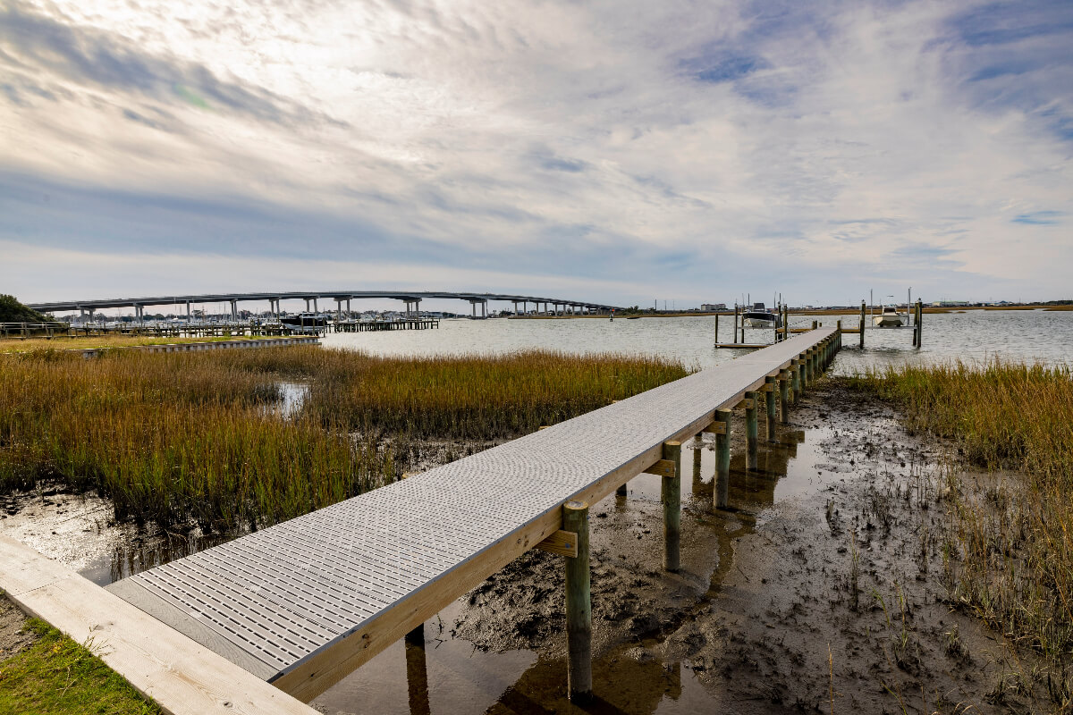 A Titan Deck is pictured. There is a marshy area below the dock and a large bridge in the background. 