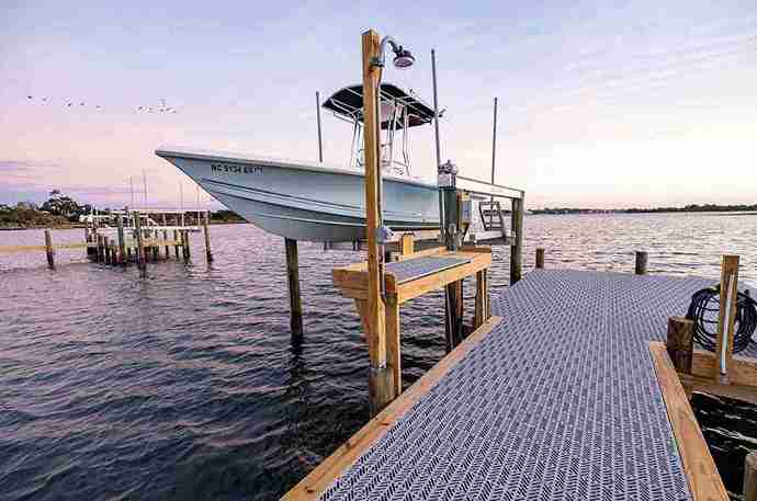 Titan Open X Boards on a wood framed dock with a blue boat on a lift over the ocean.